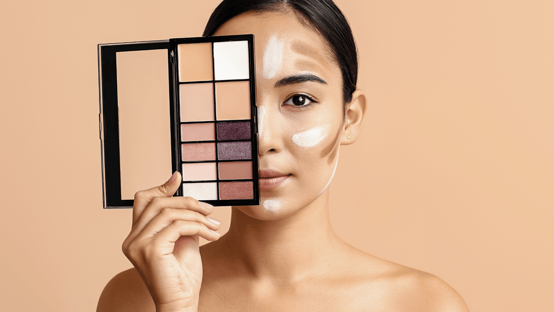 En kvinna håller en makeup-palett framför halva ansiktet. Hon har kontur- och highlight-produkter applicerade på kindbenen, pannan och hakan. Paletten innehåller olika färger för contouring och ögonskugga. Bakgrunden är ljusbeige.